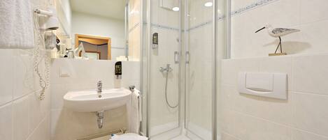 A modern bathroom with a glass-enclosed shower, a white sink, and a toilet.