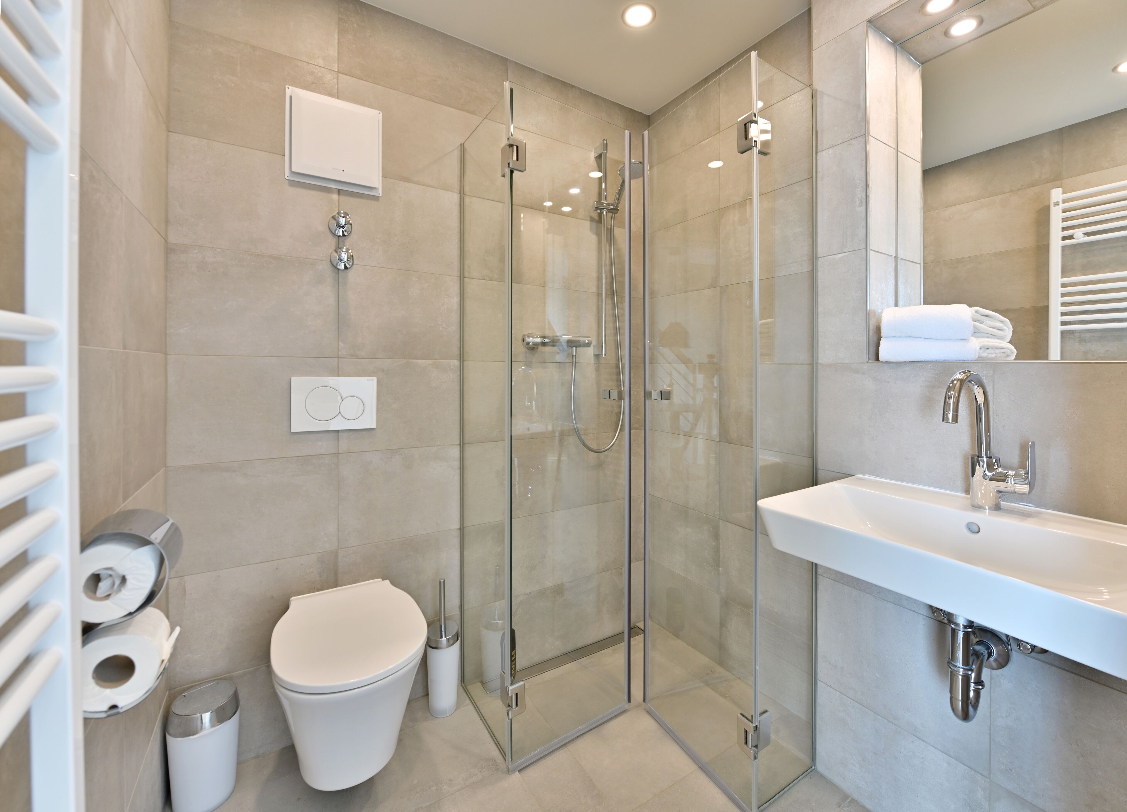 A modern bathroom with a glass-enclosed shower, a white sink, and a toilet.