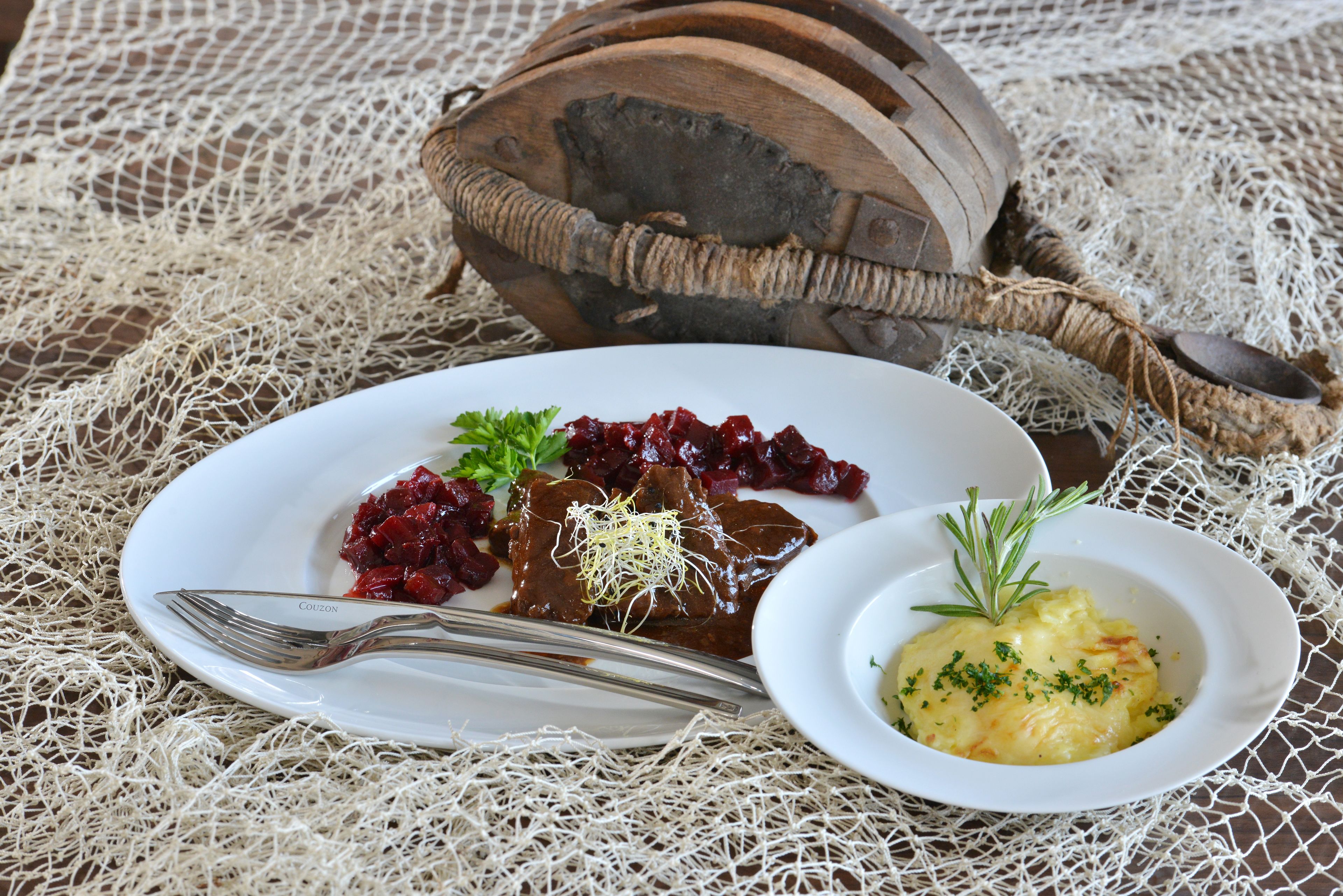 A plate of food with a fork and a wooden bowl.