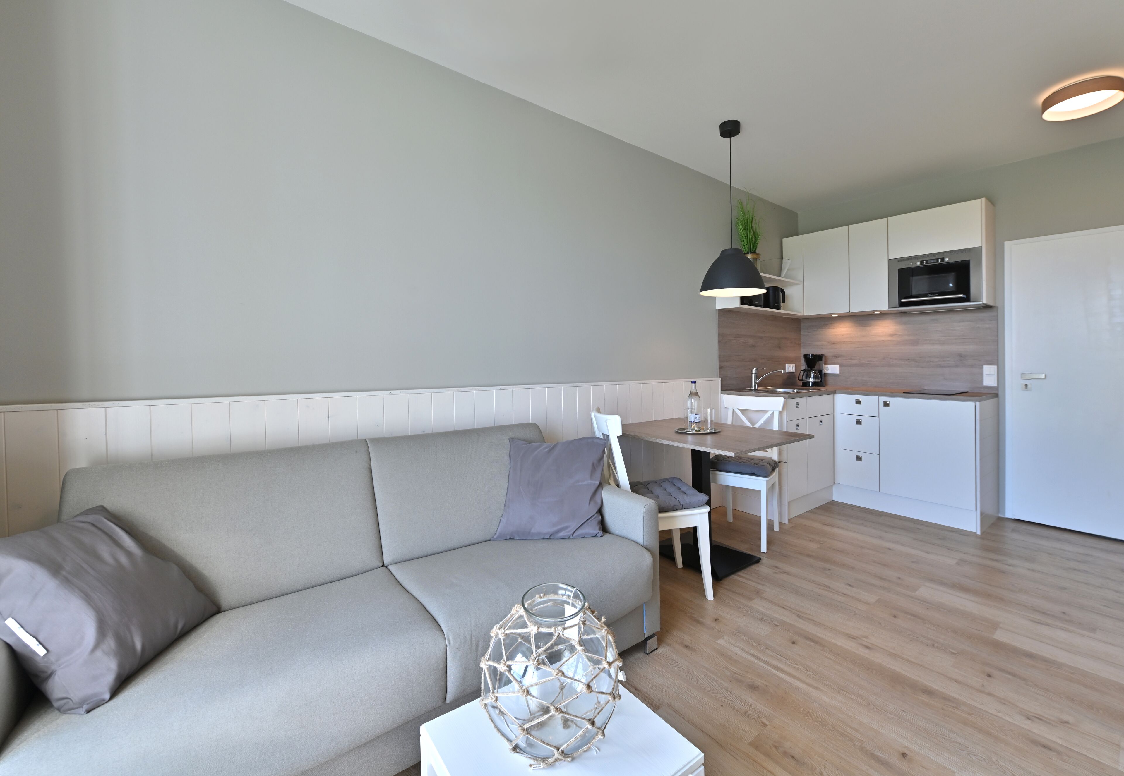 A modern living room with a sofa, a coffee table, and a dining area with a table and chairs.