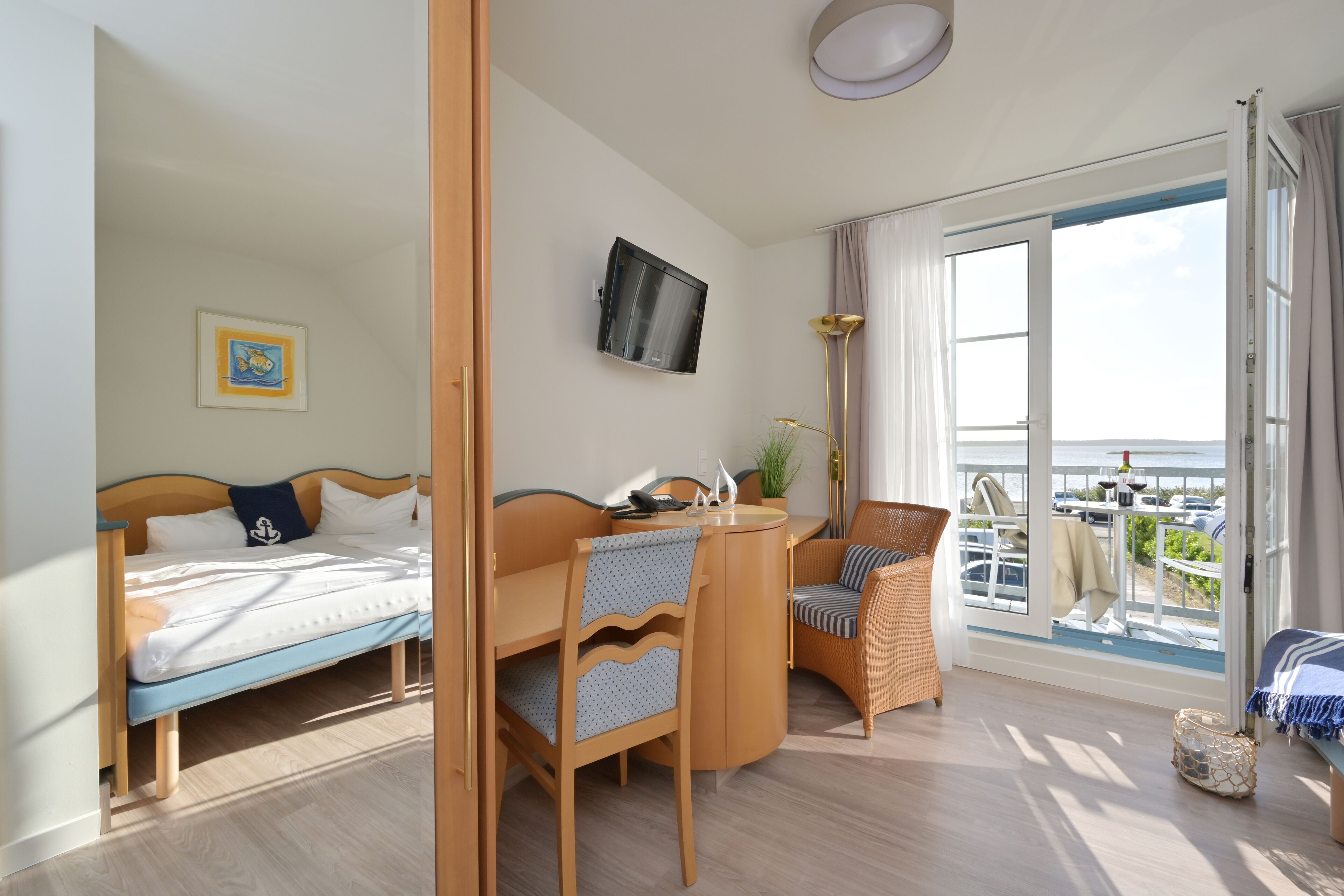 A room with a bed, a desk, a chair, a television, and a balcony with a view.
