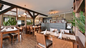 A restaurant with wooden furniture, a bar area, and large windows. - Kapitäns-Häuser Breege (Breege)