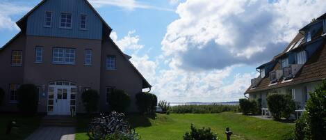 A two-story house with a large front lawn, a driveway, and a bicycle parked outside.