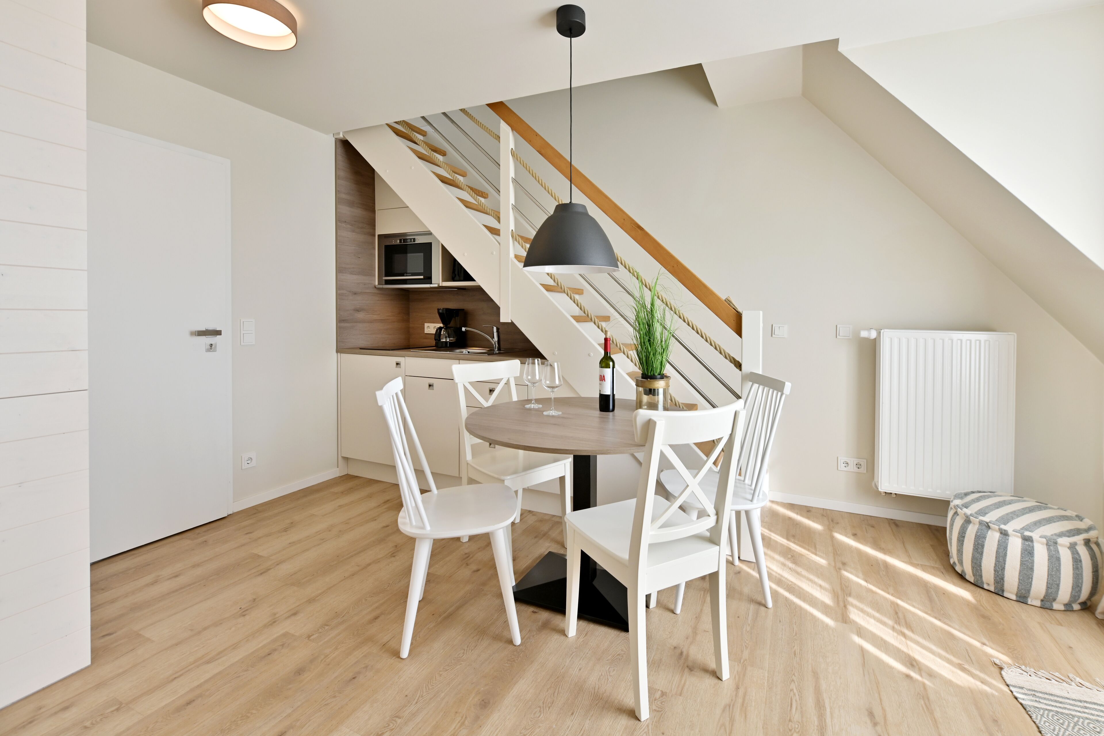 Una cocina moderna con muebles blancos, encimera de madera y un microondas integrado.