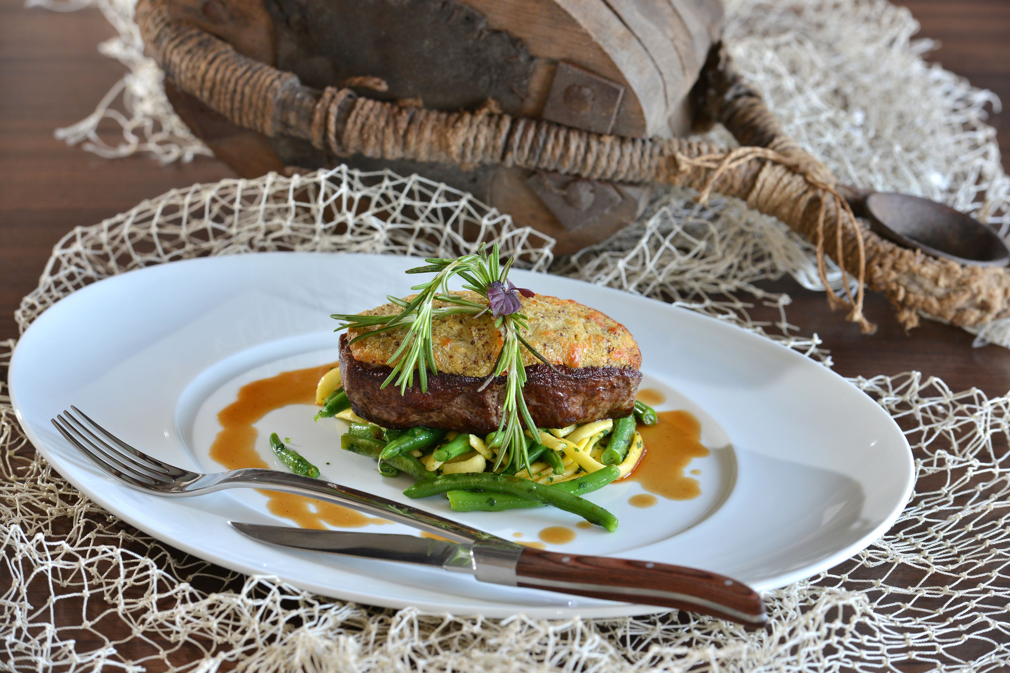 A plate of food with a fork and knife on a table with a woven placemat.
