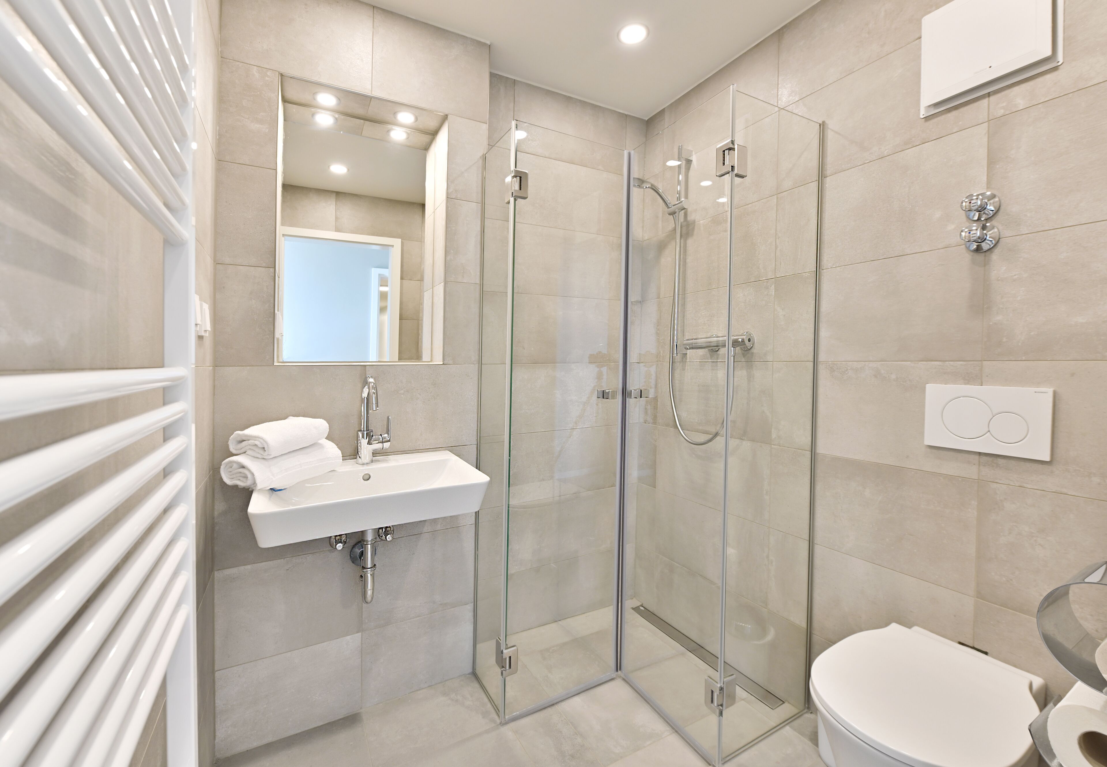 A modern bathroom with a glass-enclosed shower, a white sink, and a toilet.