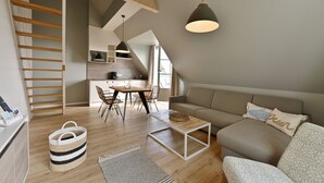 A modern loft-style living space with a staircase, a dining area, and a cozy seating area. - Kapitäns-Häuser Breege (Breege)