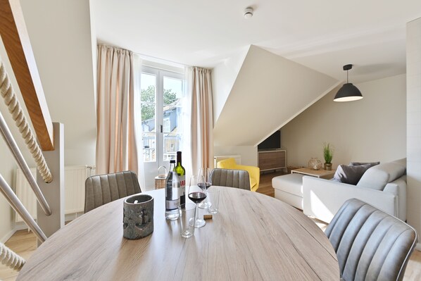 A dining area with a wooden table, chairs, and a bottle of wine.