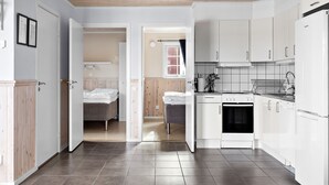 A modern kitchen with white cabinets, a stove, and a refrigerator. There is a small dining area with a table and chairs. - First Camp Sunne (Sunne)