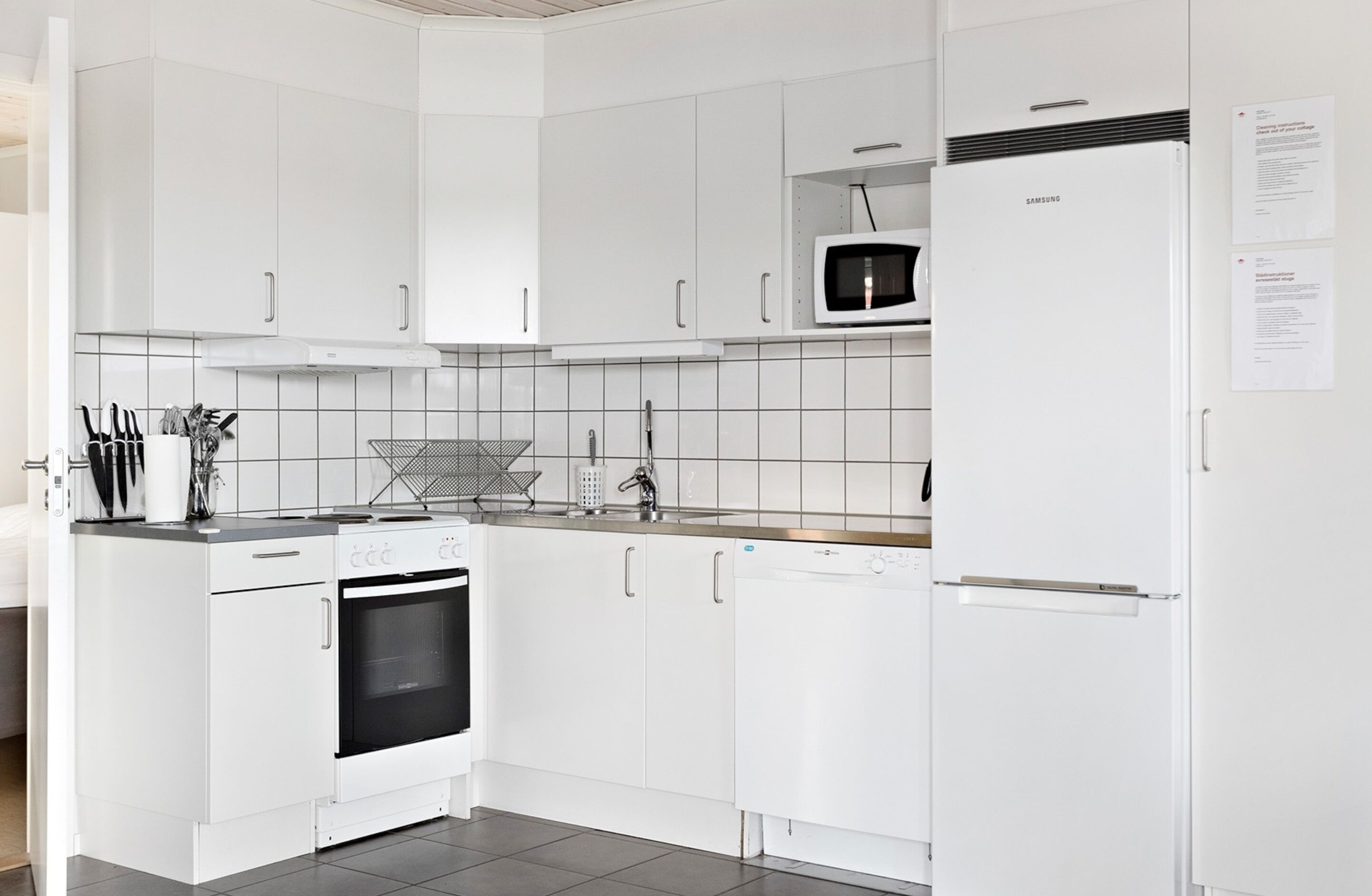 A modern kitchen with white cabinets, a microwave, a Samsung refrigerator, and a dishwasher.