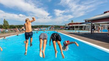 A swimming pool with people jumping and swimming.