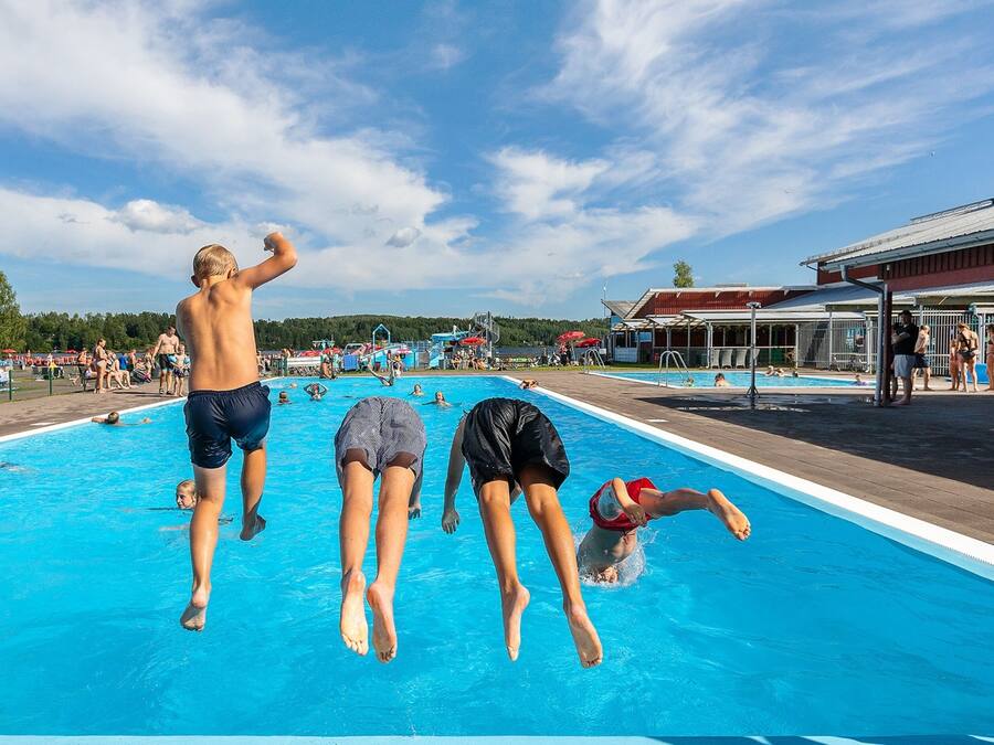 A swimming pool with people jumping and swimming.