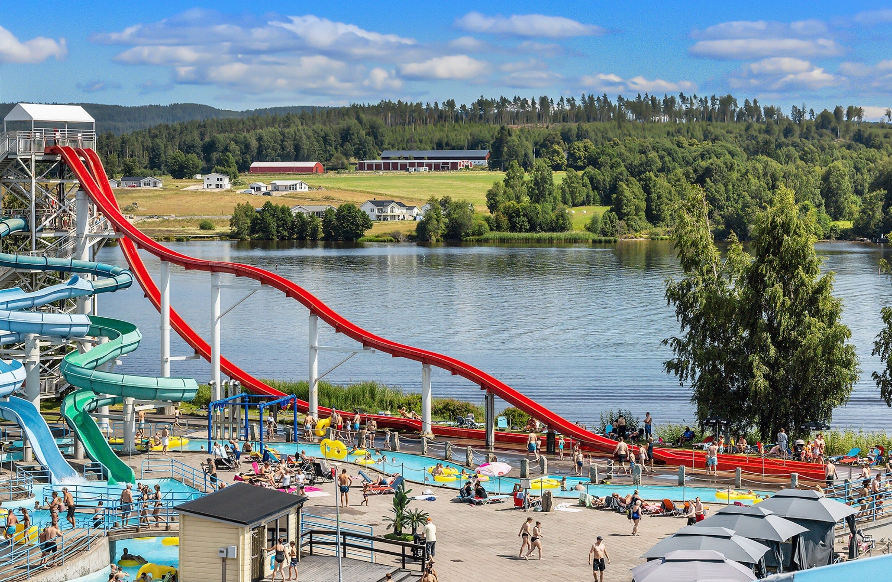 A water park with multiple water slides, a swimming pool, and a lake view.