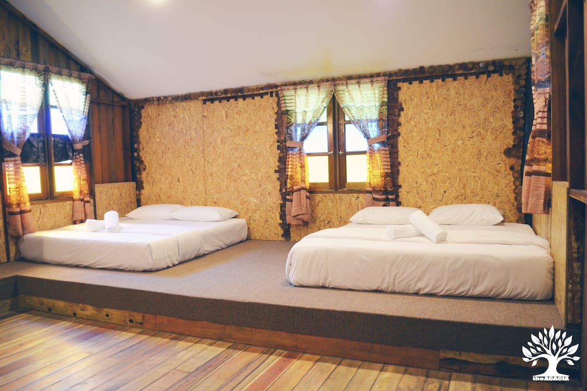 Una habitación con dos camas, pisos de madera y un diseño rústico en la pared.