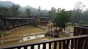 A riverside hotel with a wooden deck, a thatched-roof pavilion, and a view of a river. - The Acacia Retreat (Bentong)
