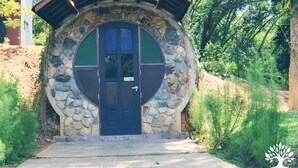 A stone building with a circular door, surrounded by greenery. - The Acacia Retreat (Bentong)