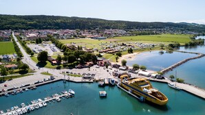 Un puerto deportivo con barcos amarrados, un gran ferry amarillo y un pueblo al fondo.