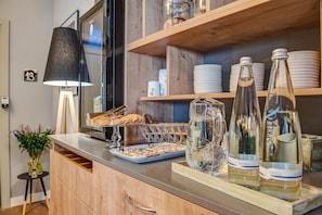 A kitchen counter with a tray of cookies, a glass jar, and two bottles of wine. - Landhotel Diana (Teltow)