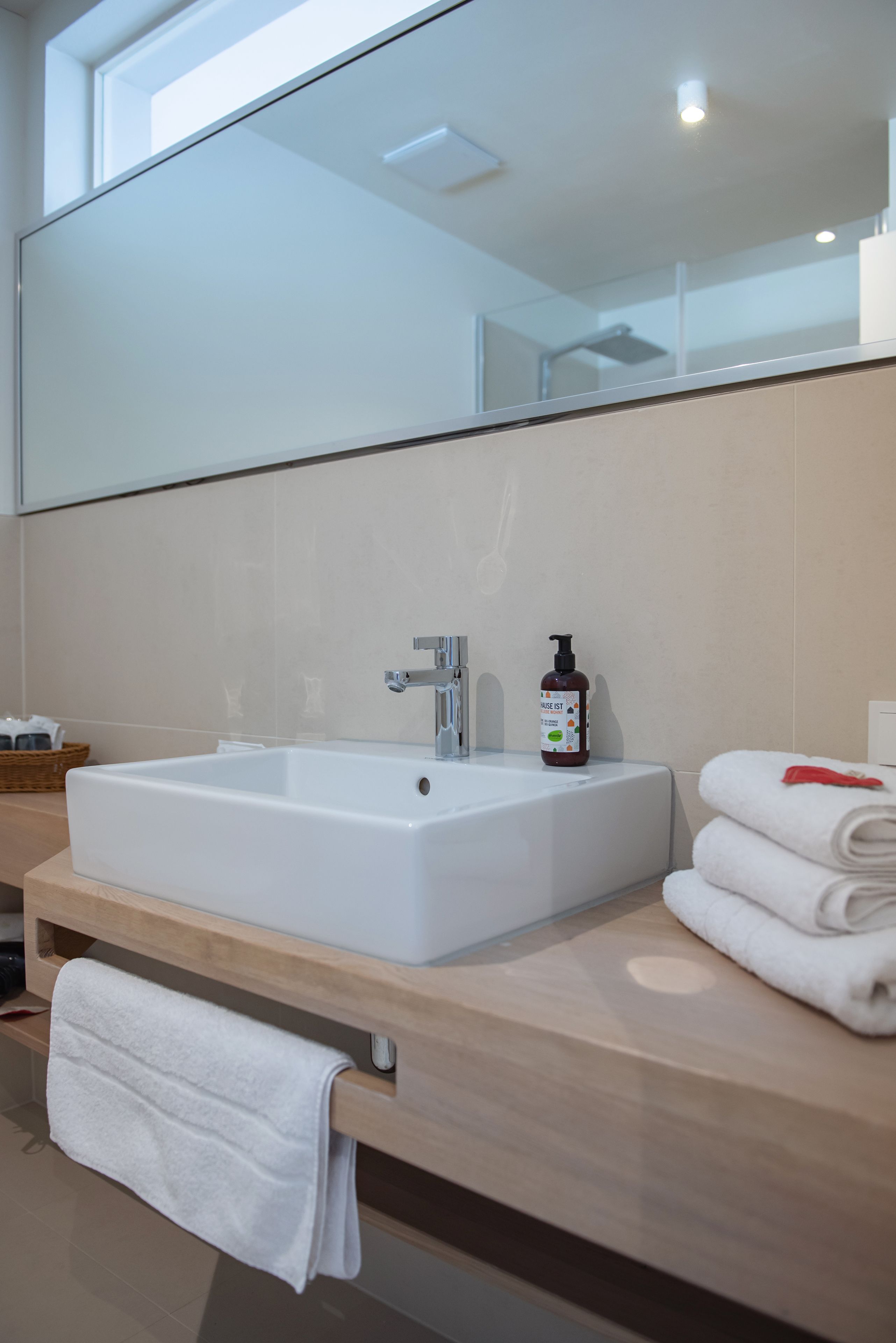A modern bathroom with a large white sink, a mirror, and a wooden vanity.