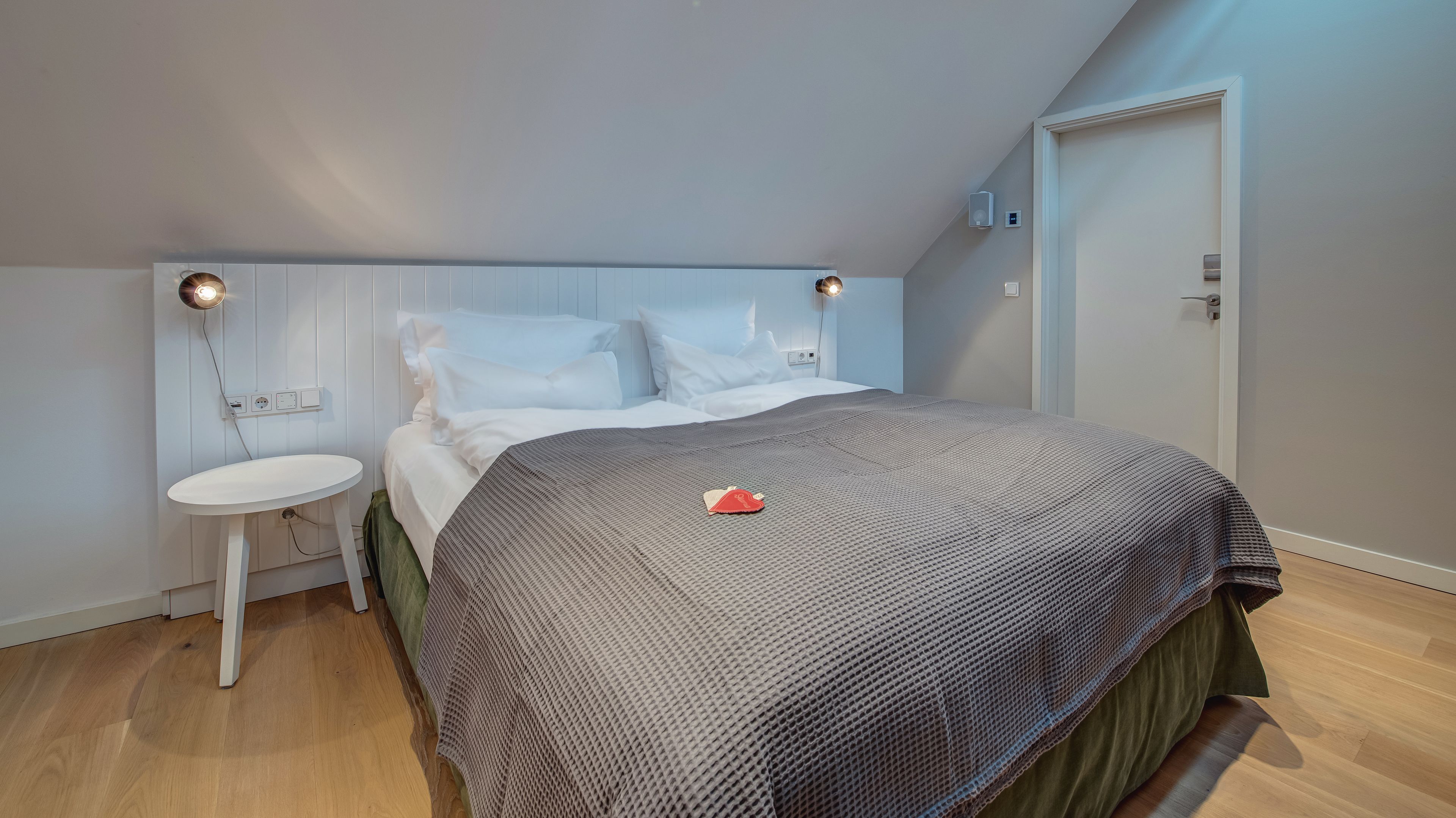 A bedroom with a bed, bedside table, and a wall-mounted light fixture.