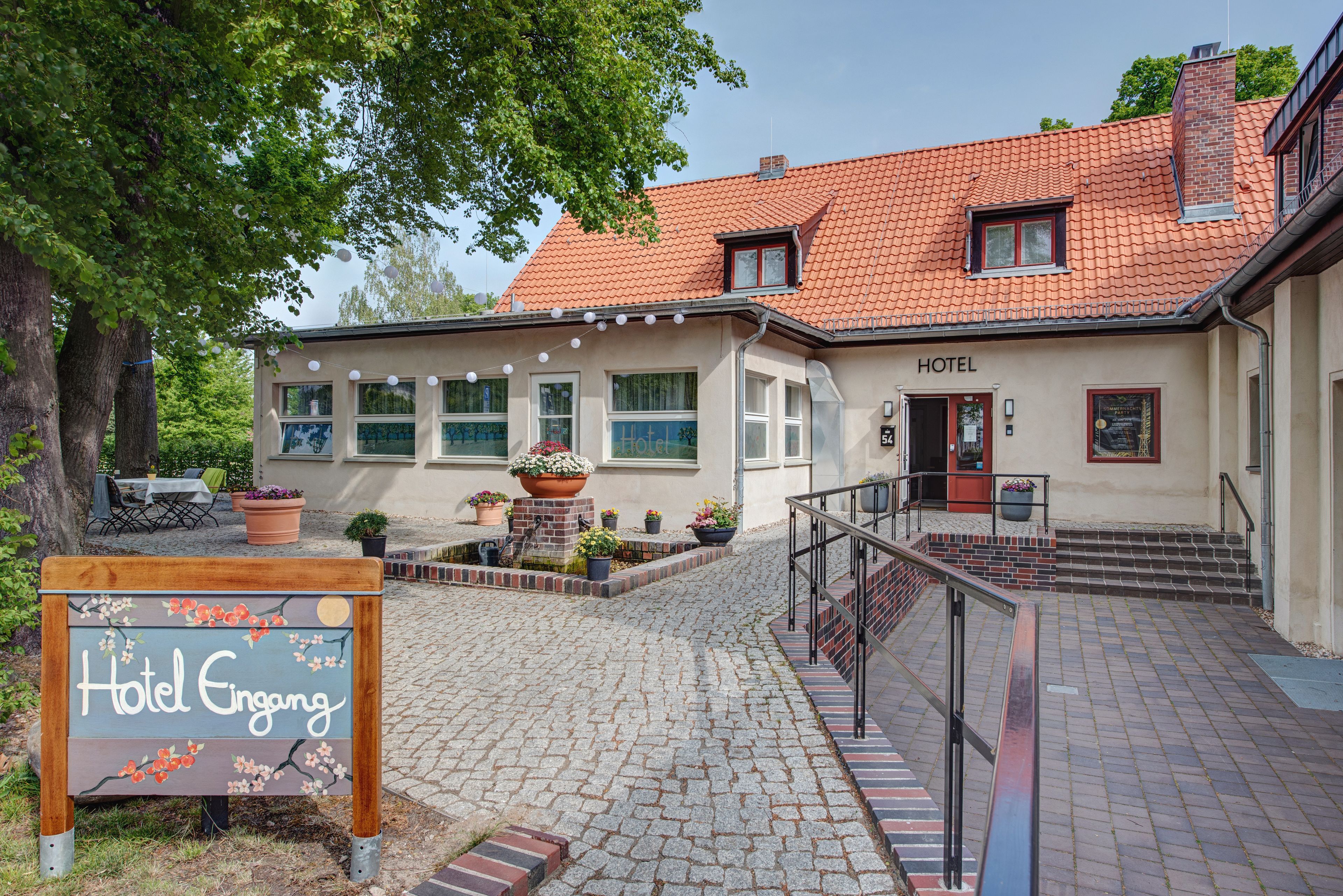 A hotel with a tiled roof, a signboard, and a paved walkway leading to the entrance.