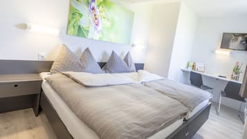 Un dormitorio moderno con cama, mesitas de noche, escritorio y una silla.
