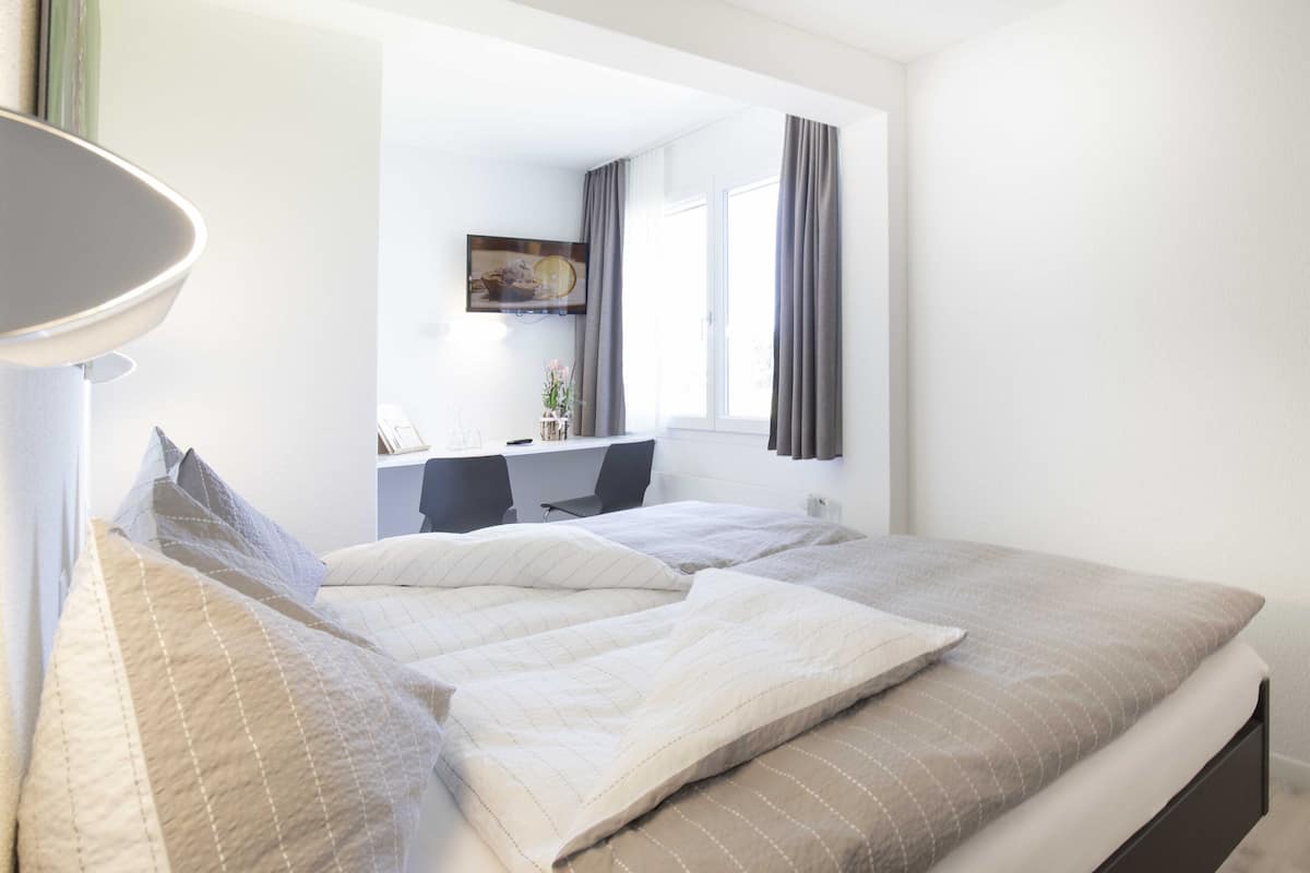 A bedroom with a bed, a desk, and a chair.