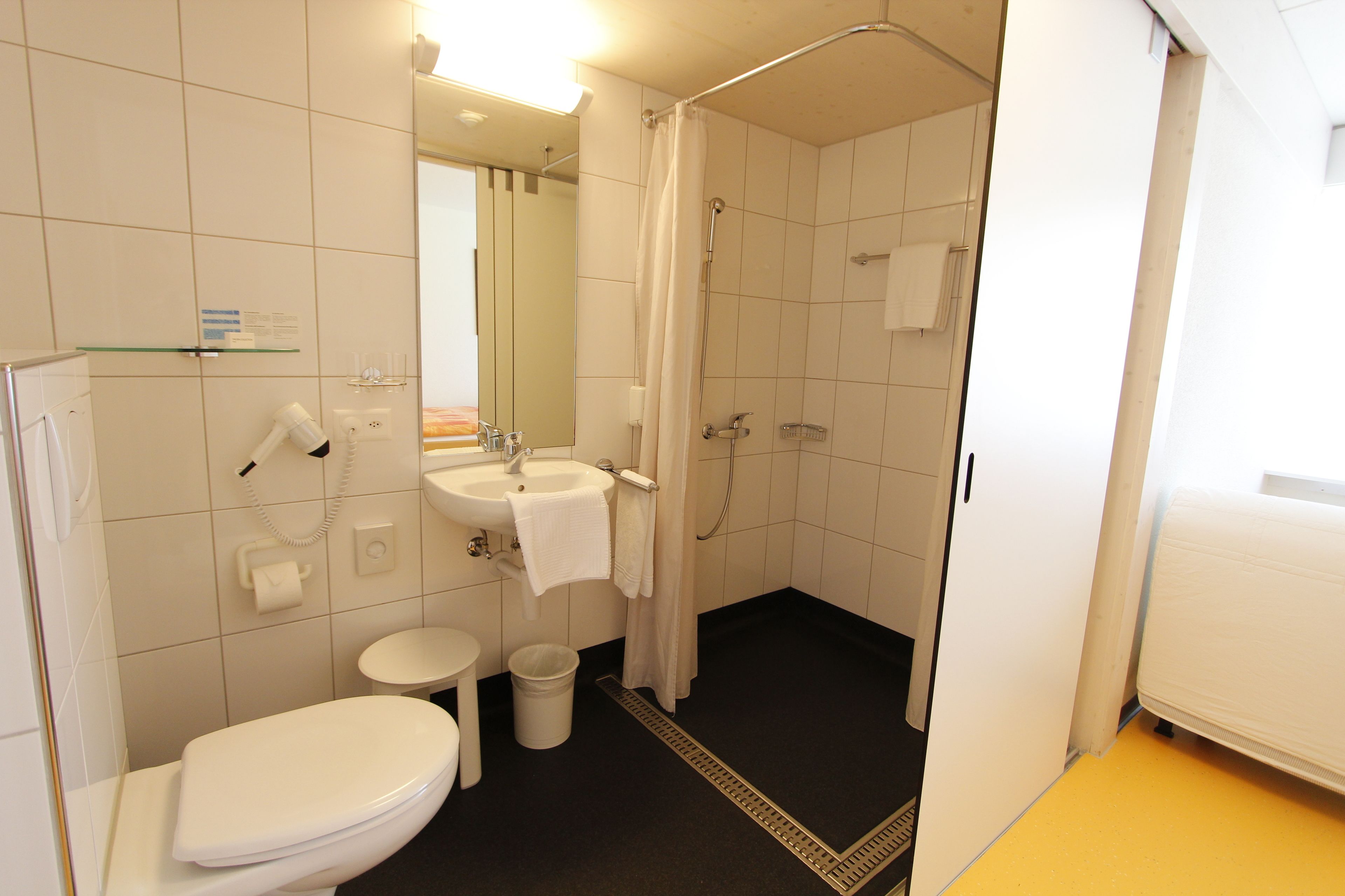 Une petite salle de bain propre, équipée de toilettes, d’un lavabo et d’une douche.
