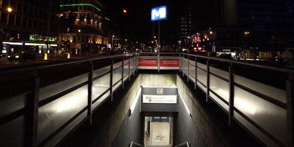 A nighttime view of a pedestrian bridge with a sign indicating a metro station. - Hotel City Center (Brussels)