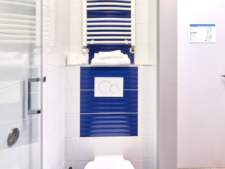 Une salle de bain moderne équipée de toilettes, d’un bidet et d’un porte-serviettes.