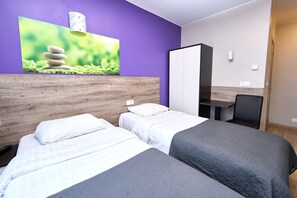 Ein Zimmer mit zwei Betten, einem Schreibtisch und einem Kleiderschrank.
