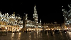 Una plaza histórica con edificios ornamentados, una torre destacada y una multitud de personas.