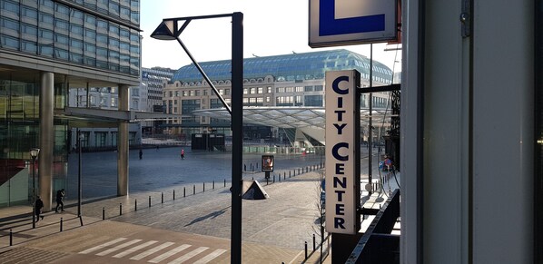 Eine Innenstadt mit einem modernen Glasgebäude, einem 'CITY CENTER'-Schild und einer Fußgängerüberweg.