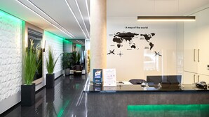 Un área de recepción moderna con un mapa mundial, una mesa de recepción y plantas en macetas.
