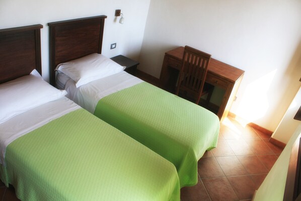 A room with two beds, a nightstand, a chair, and a small table.
