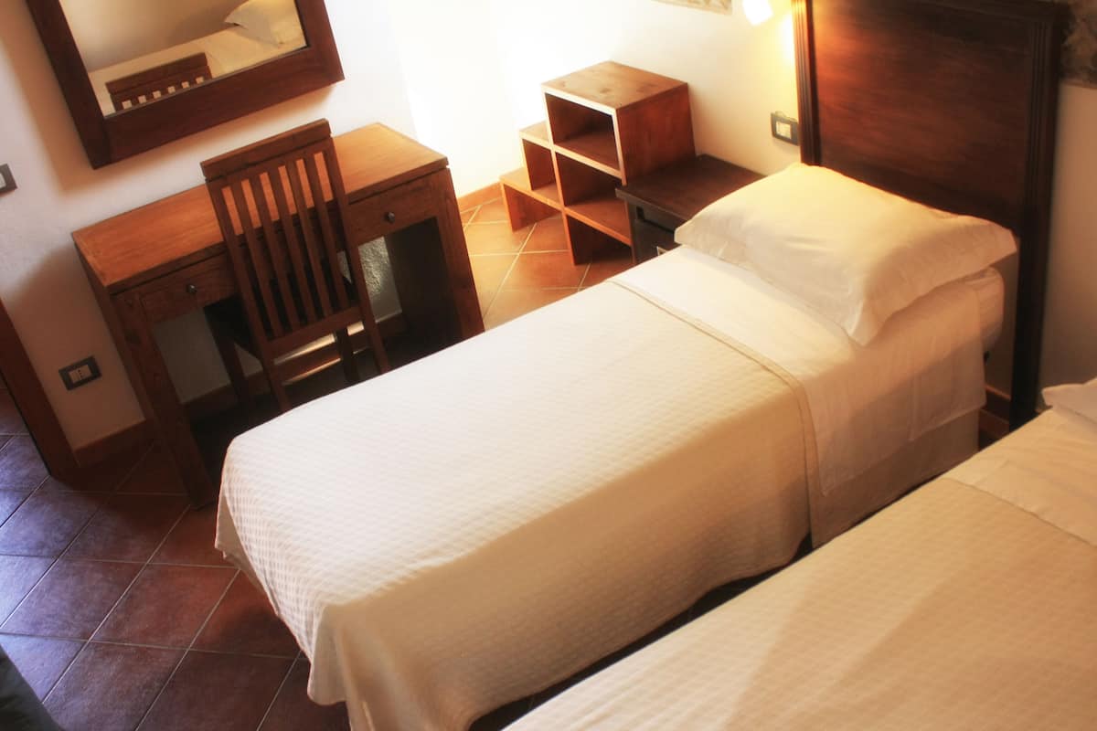 A bedroom with two beds, a wooden desk, and a chair.