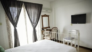 Ein Schlafzimmer mit Bett, Schreibtisch, Stuhl, Spiegel und Fernseher an der Wand.