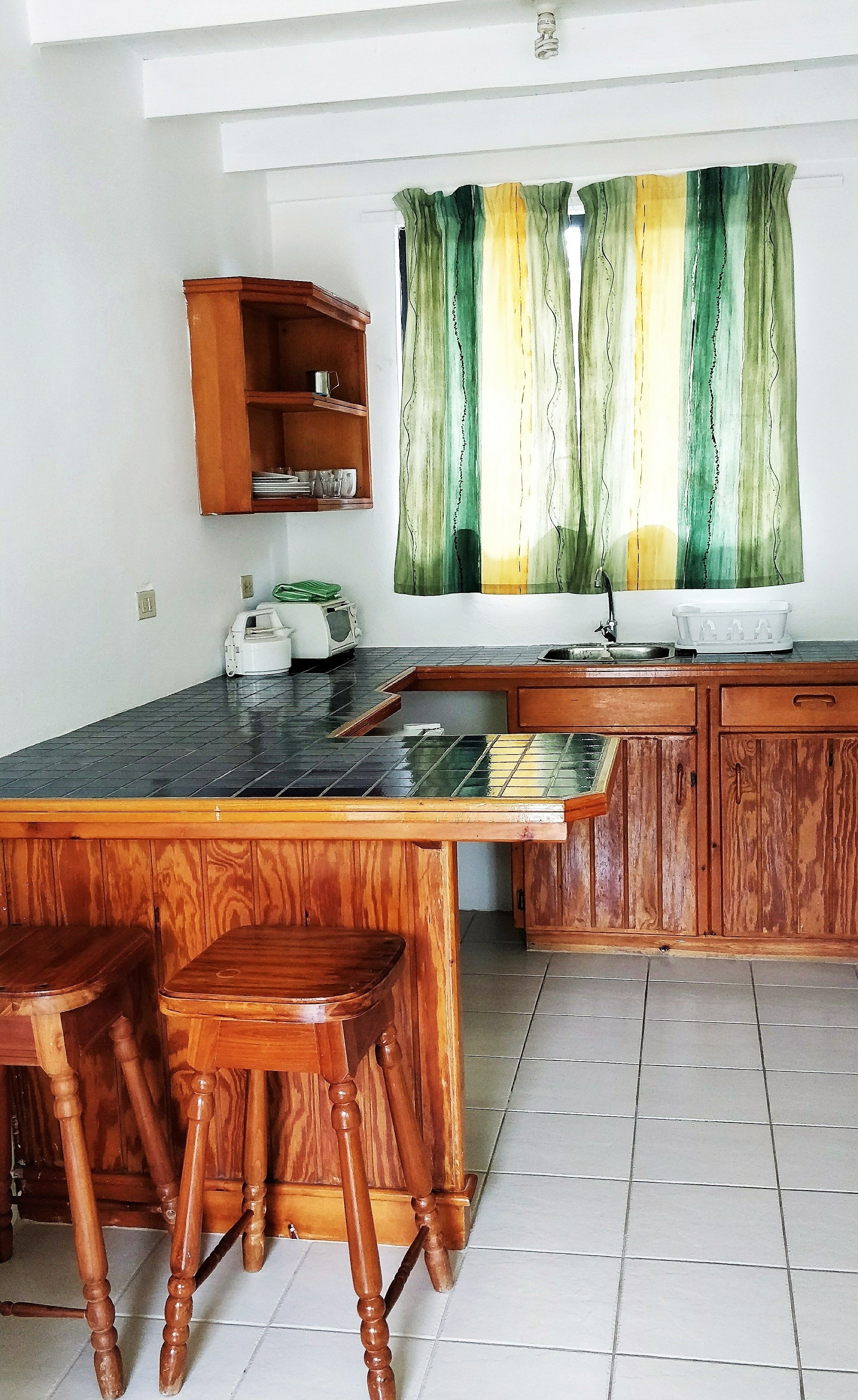A kitchen with a wooden island, bar stools, a microwave, and a cabinet.