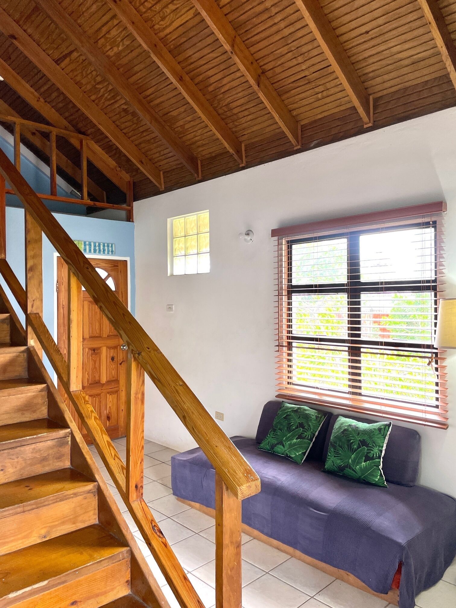 A wooden staircase leading to a room with a window and a sofa.