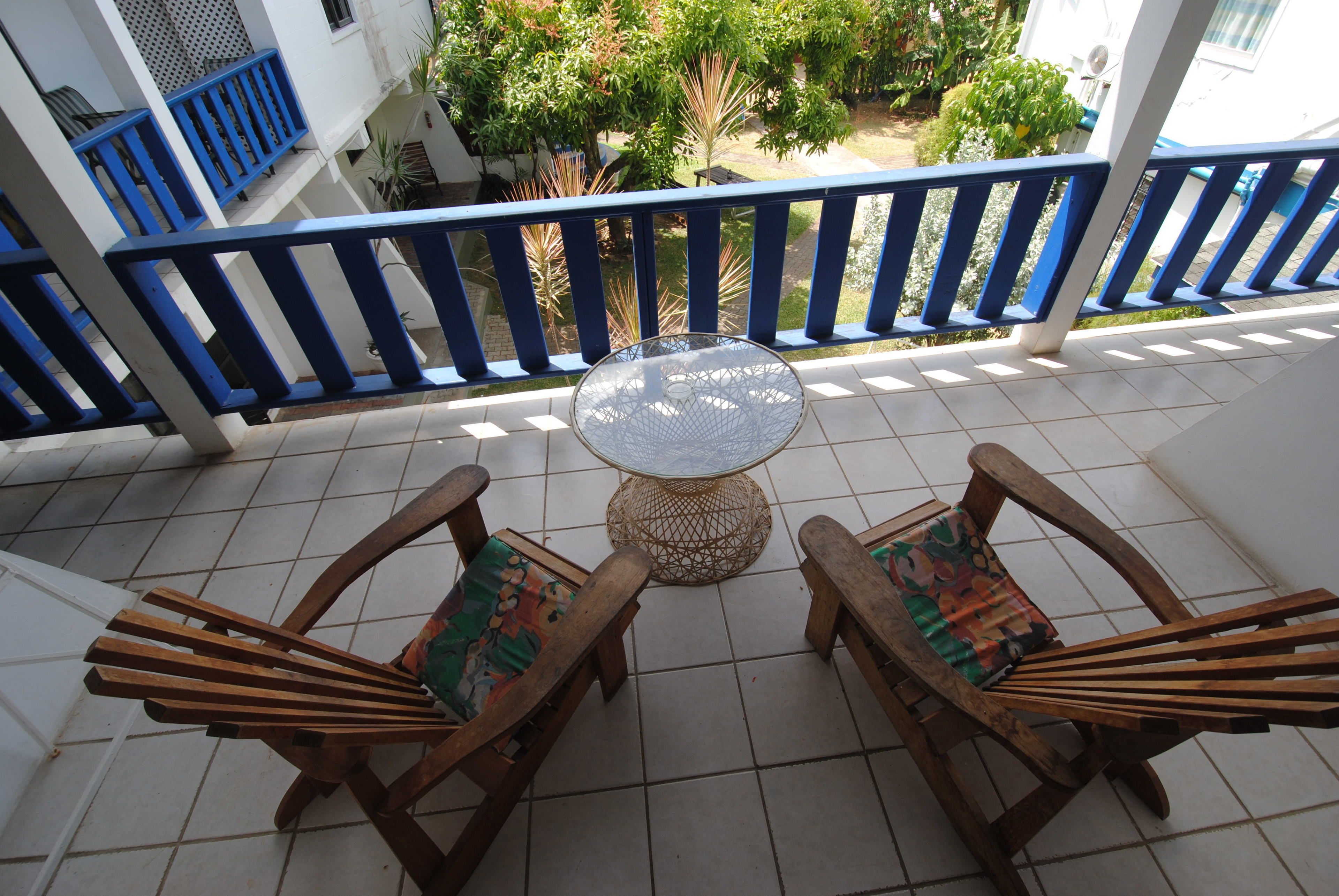 Un balcon avec deux chaises en bois et une table ronde.