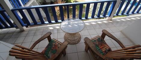 Un balcon avec deux chaises en bois et une table ronde.