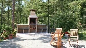 Eine Außenpatio-Terrasse mit Kamin aus Stein, zwei Holzstühlen und Kiesboden.