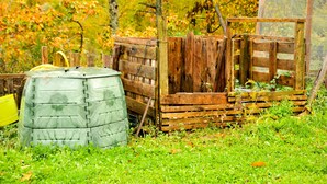 Eine ländliche Außenanlage mit Holzlattenzaun, einem grünen Fass und einem gelben Eimer.