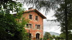 Ein rustikales Steinhaus mit traditioneller Gestaltung, das einen zentralen Bogen und mehrere Fenster aufweist.