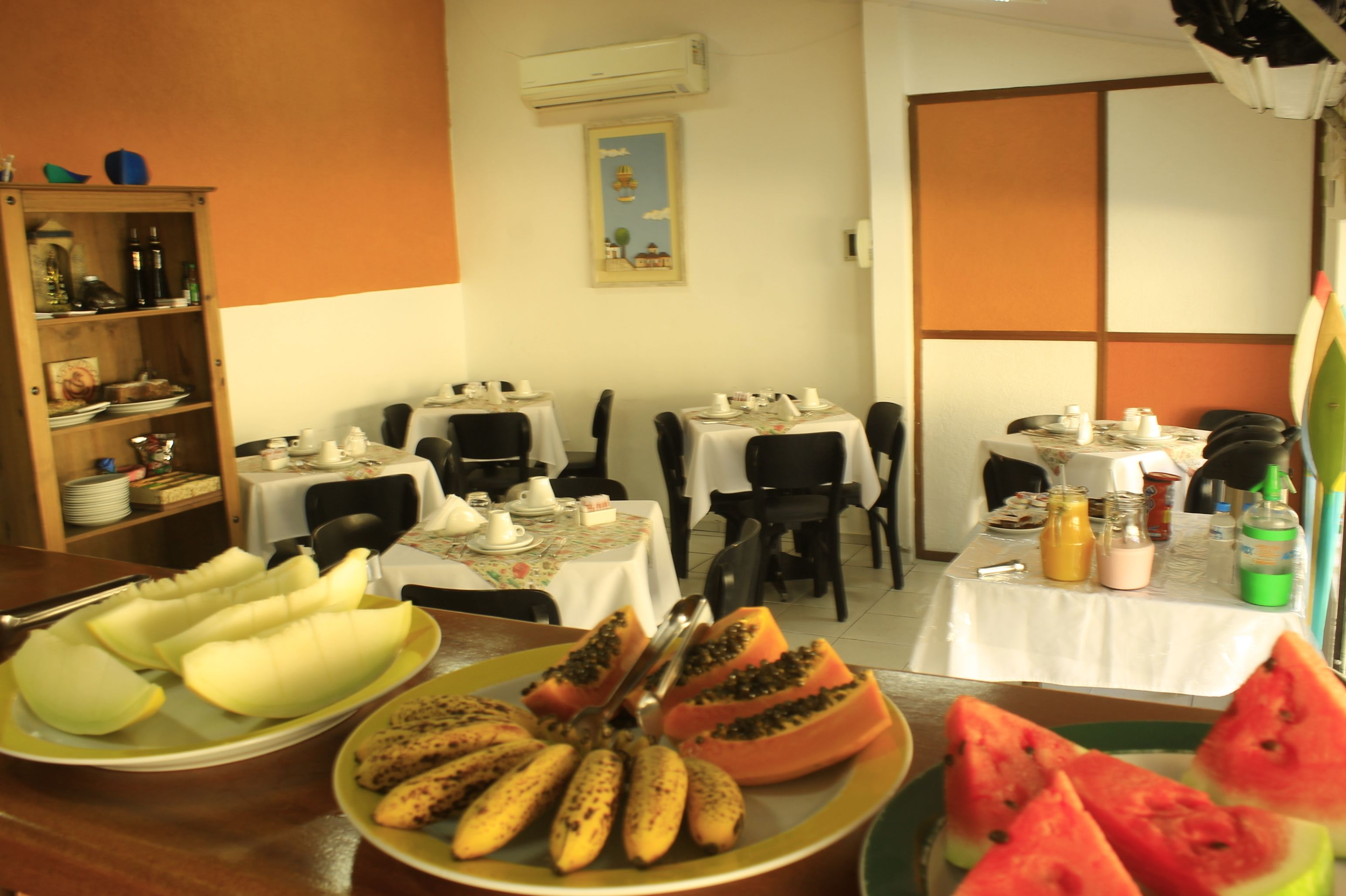 A dining area with tables set for breakfast, featuring plates of fruit and breakfast items.