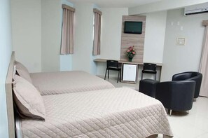 A hotel room with a bed, a desk, two chairs, and a TV mounted on the wall. - Serras Hotel (Rondonopolis)