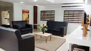 A modern living room with two black sofas, a coffee table, and a small side table. - Serras Hotel (Rondonopolis)