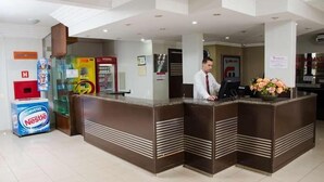 A reception area with a counter, a Nestlé vending machine, and a sign for 'EMMANTELLA'. - Serras Hotel (Rondonopolis)