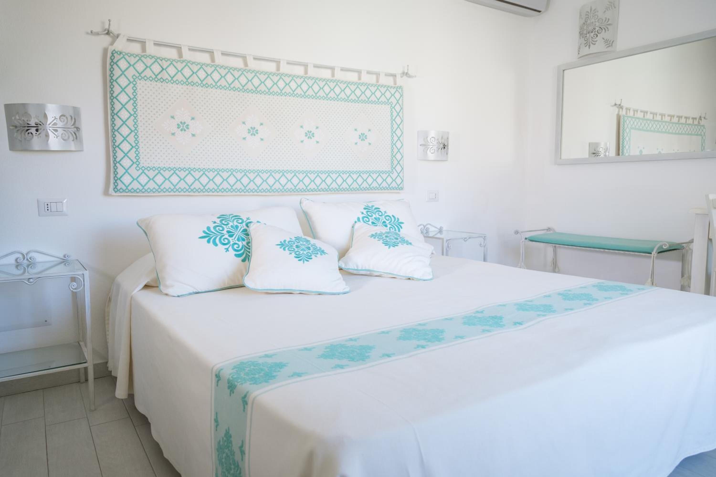 Un dormitorio con cama, mesitas de noche, un espejo y un adorno en la pared.
