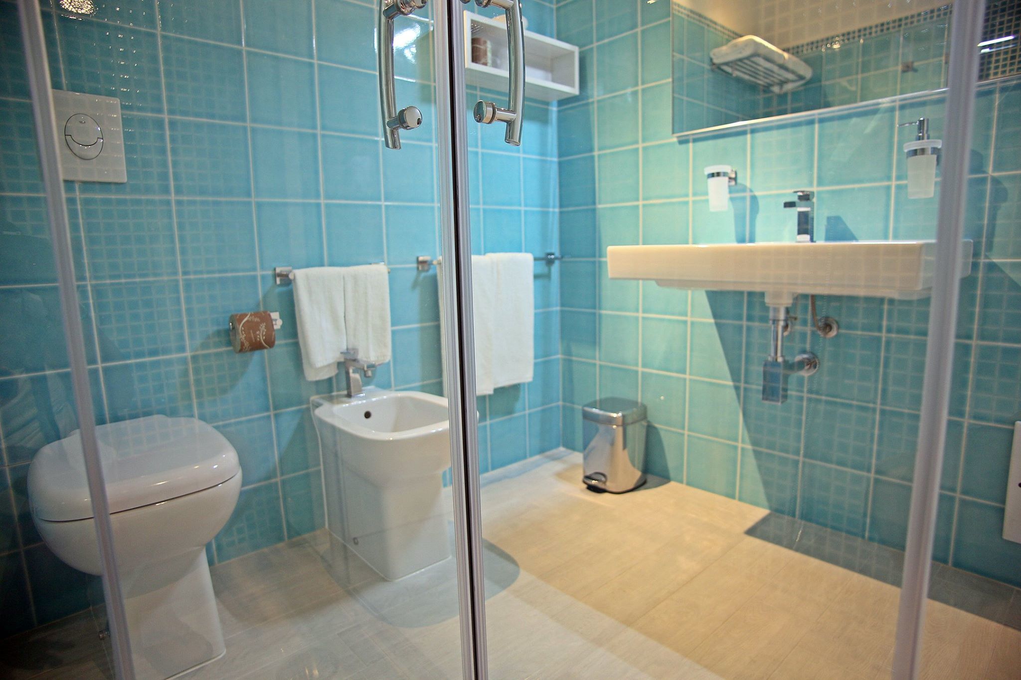 Ein Badezimmer mit Toilette, Bidet und Duschkabine aus Glas.